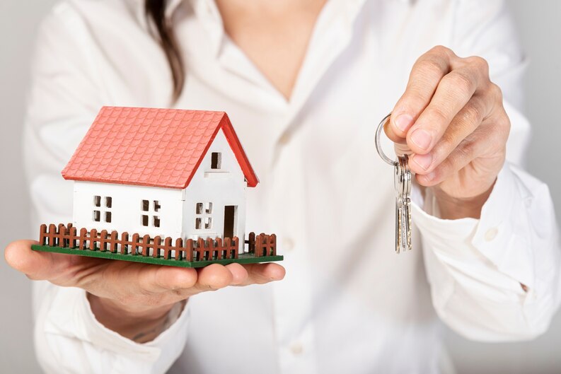 Real estate agent holding a house model and keys, symbolizing the services of a Top Real Estate Agent in Orange County