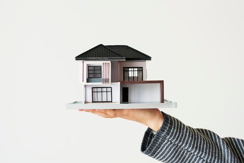 Hand holding a house model, symbolizing property transactions with a Top Real Estate Agent in Irvine