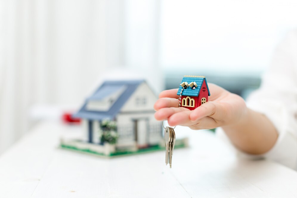 Top real estate agent in Laguna Beach holding a house model and keys, representing home ownership