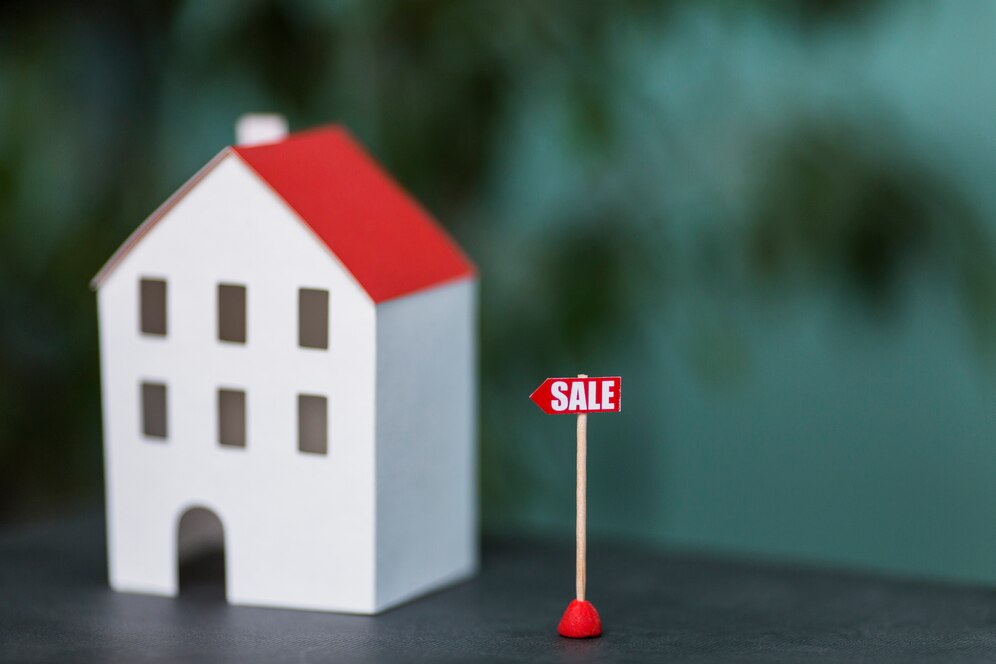 Miniature house model with "For Sale" sign - Top real estate agent in Aliso Viejo.