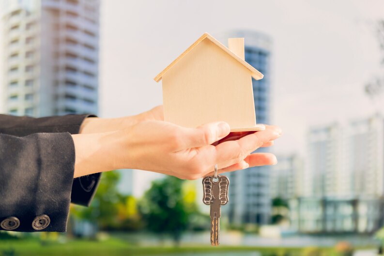 Female hand holding a wooden house model with keys - Top real estate agent in Aliso Viejo.